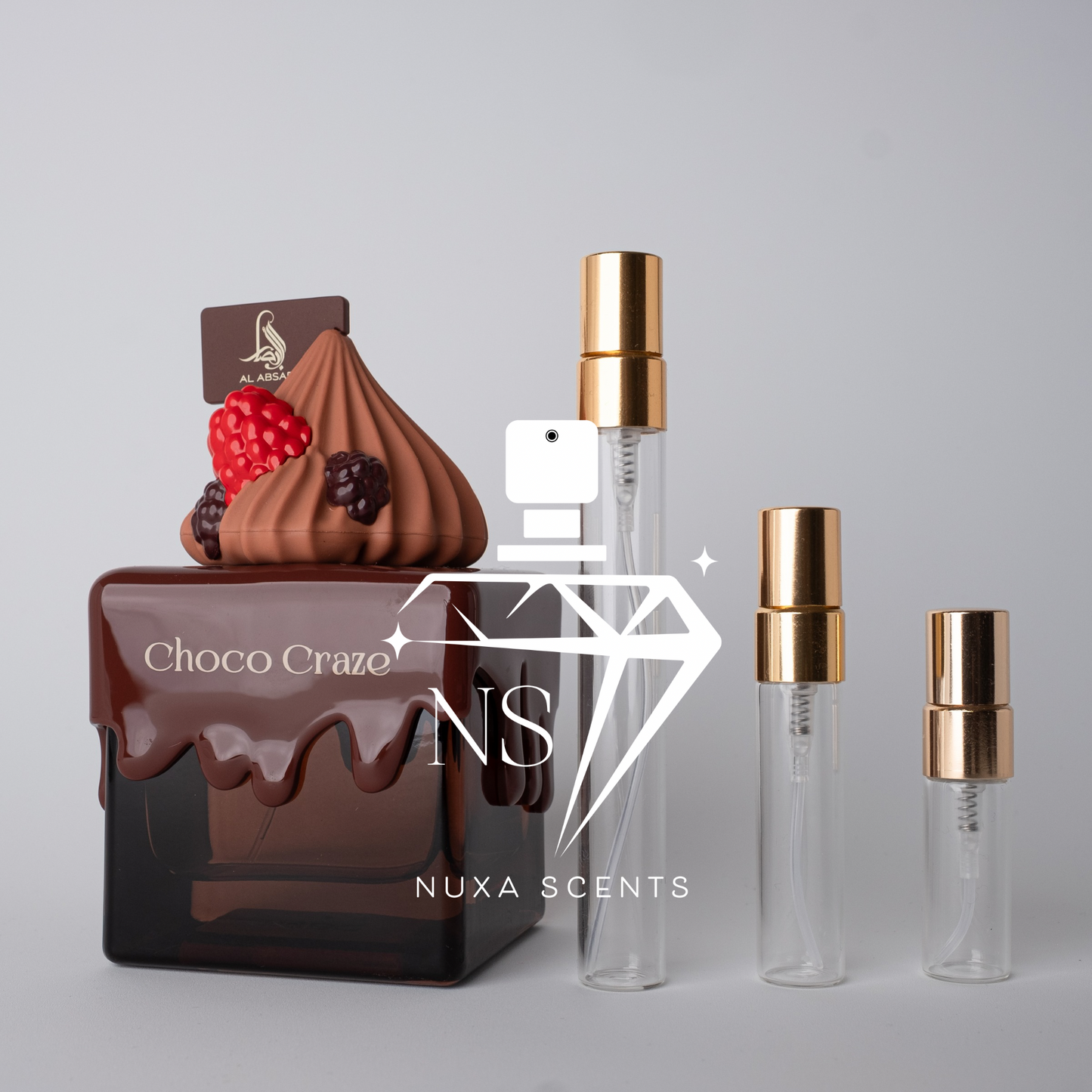 Chocolate-themed perfume bottle with 'Choco Craze' branding and Nuxa Scents bottles on a gray background.