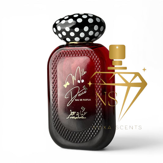 A bottle of Mila Dora Eau De Parfum with a glossy red body, black and white polka dot cap, and a gold atomizer nozzle. A gold watermark logo for 'NS Scents' is overlaid on the right side of the image.