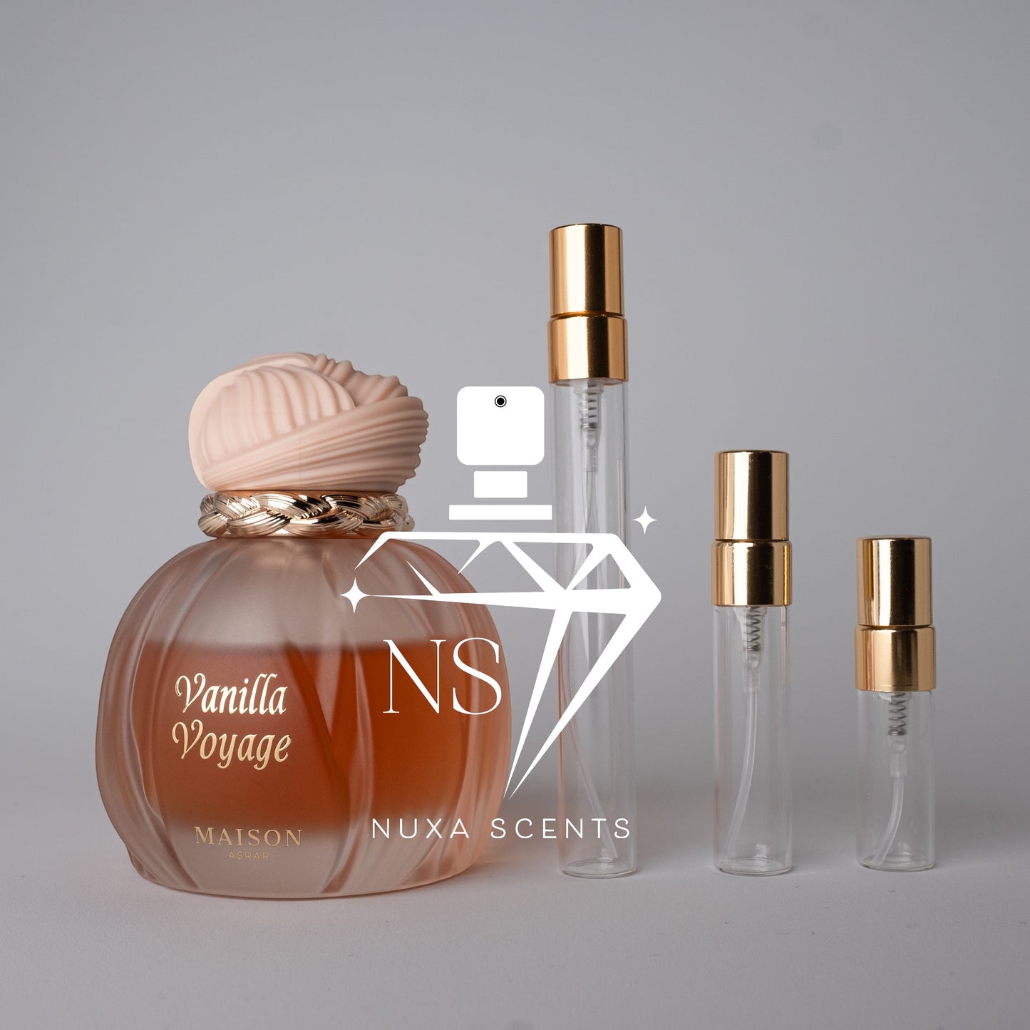 Perfume bottle labeled 'Vanilla Voyage' by Maison Asrar with two smaller bottles on a gray background.