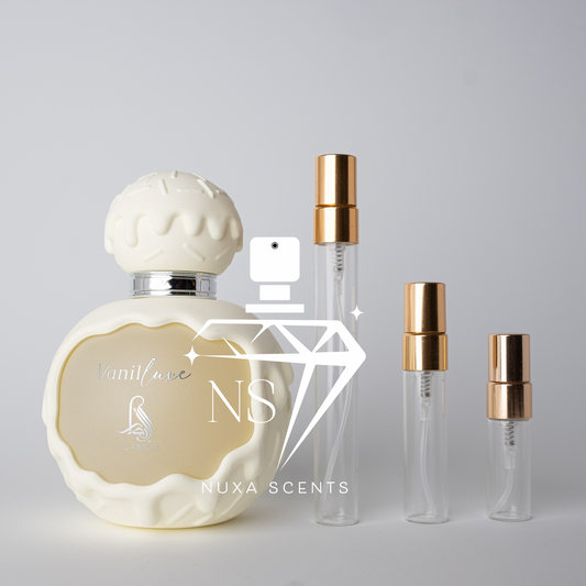 Perfume bottle with gold cap and smaller bottles on a gray background, featuring Nuxa Scents branding.
