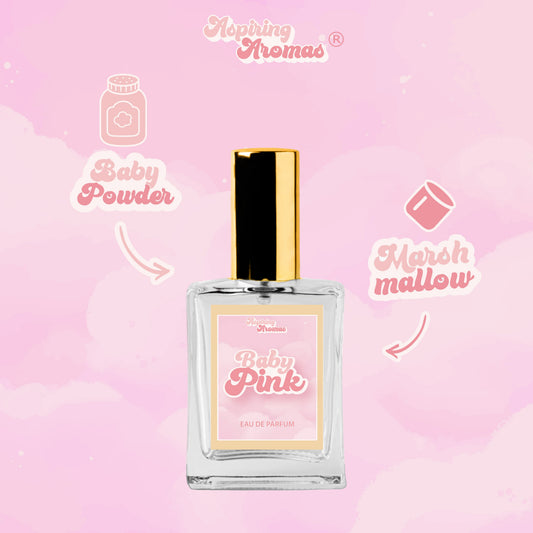 A perfume bottle labeled 'Baby Pink' by Aspiring  Aromas, centered on a soft pink cloud background with decorative text reading 'Baby Powder' and 'Marshmallow'.