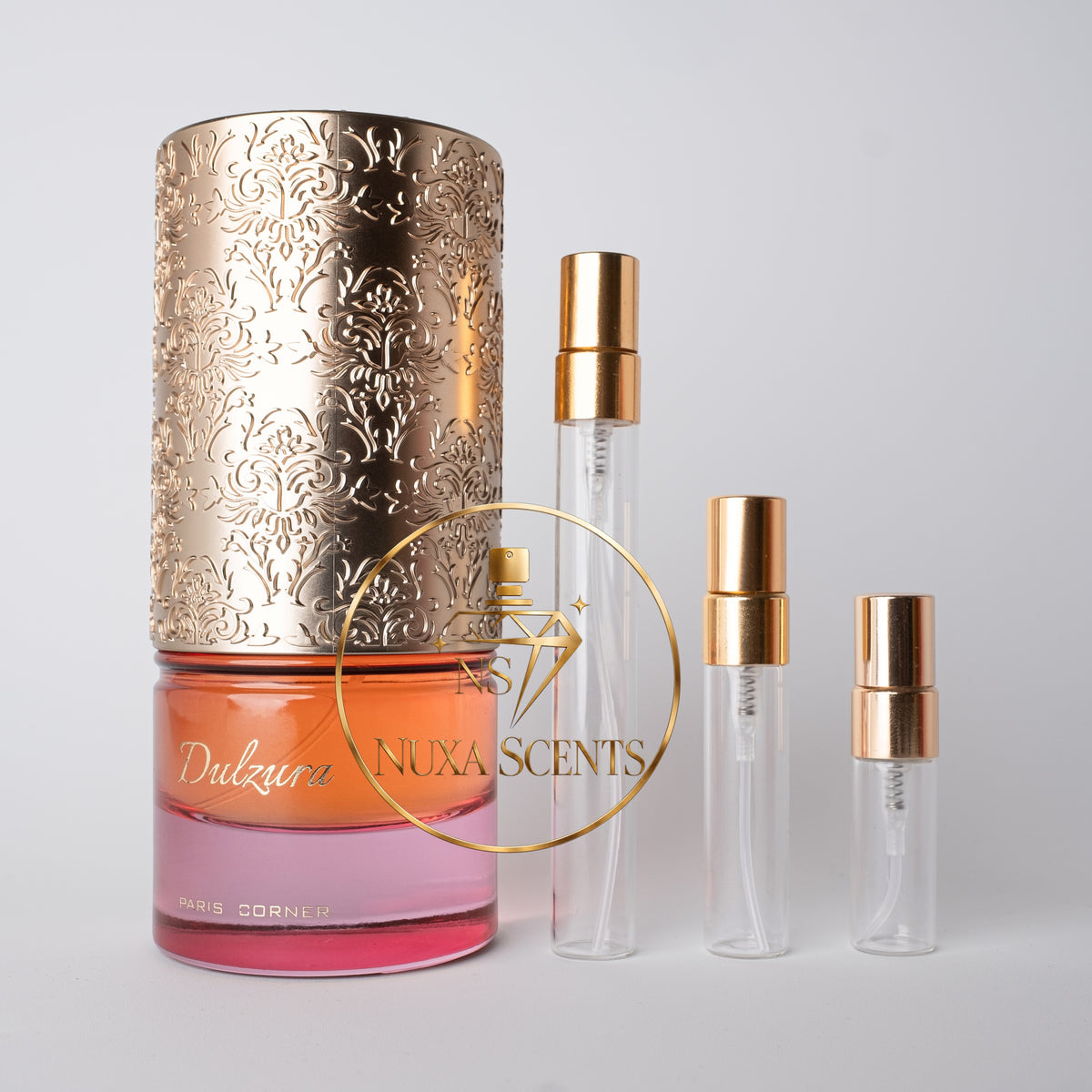 A perfume bottle with a large ornate gold cap and three clear glass travel atomizer vials with gold collars, arranged on a light gray background. A gold circular logo overlay reads 'Dulzura' and 'NUXA SCENTS'.