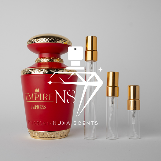 Red perfume bottle with gold accents and smaller clear bottles with gold caps on a gray background