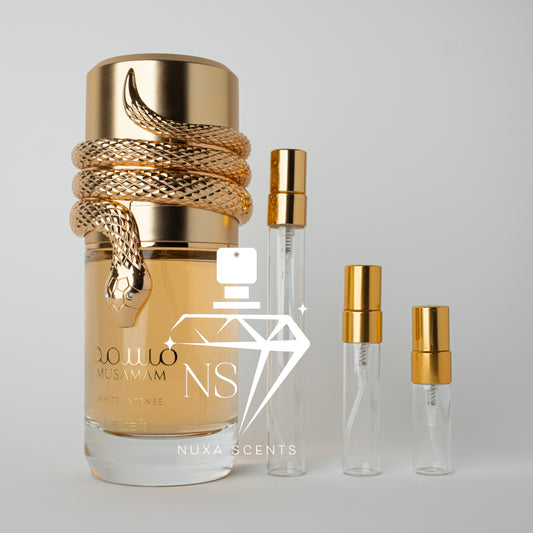 Gold and glass perfume bottle with smaller bottles on a light gray background