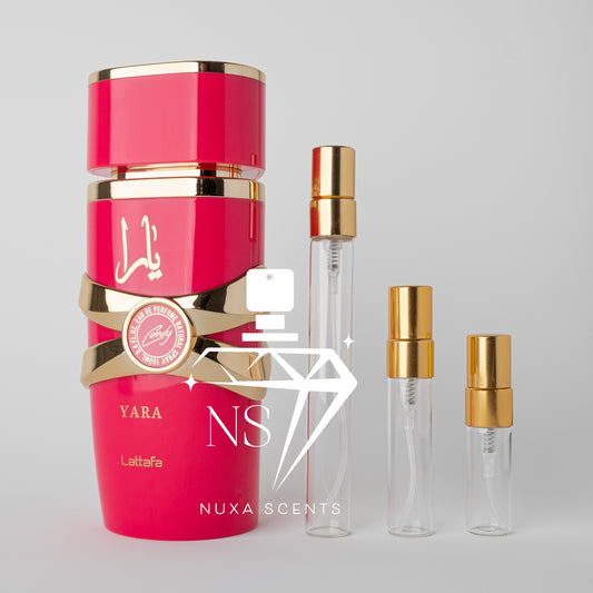 Pink perfume bottle with gold accents and clear sample bottles on a gray background