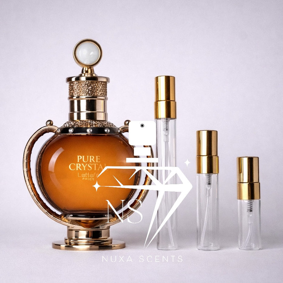 Perfume bottle with gold accents and 'PURE CRYSTAL' text, accompanied by smaller clear bottles with gold caps on a light gray background.