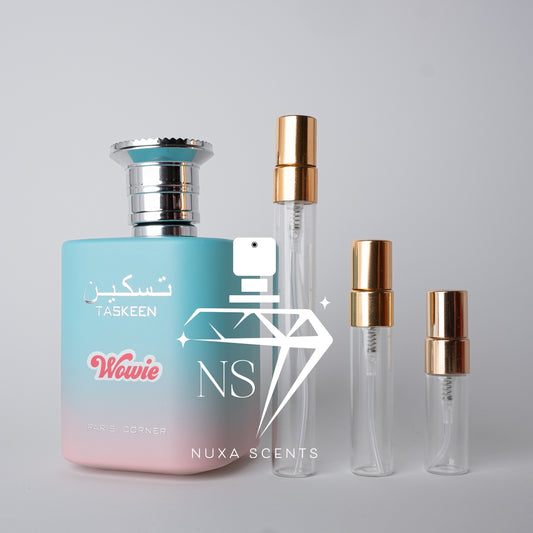 Perfume bottle with gradient design and two clear bottles with gold caps on a gray background