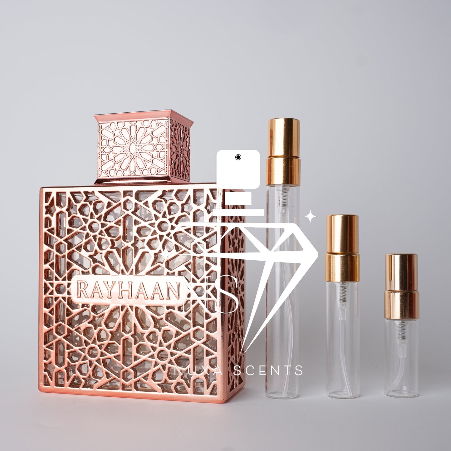 Rose gold and clear perfume bottles with 'RAYHAAN' branding on a gray background