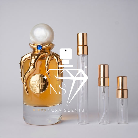 Perfume bottle with gold cap and clear body, accompanied by smaller perfume bottles with gold caps on a gray background.