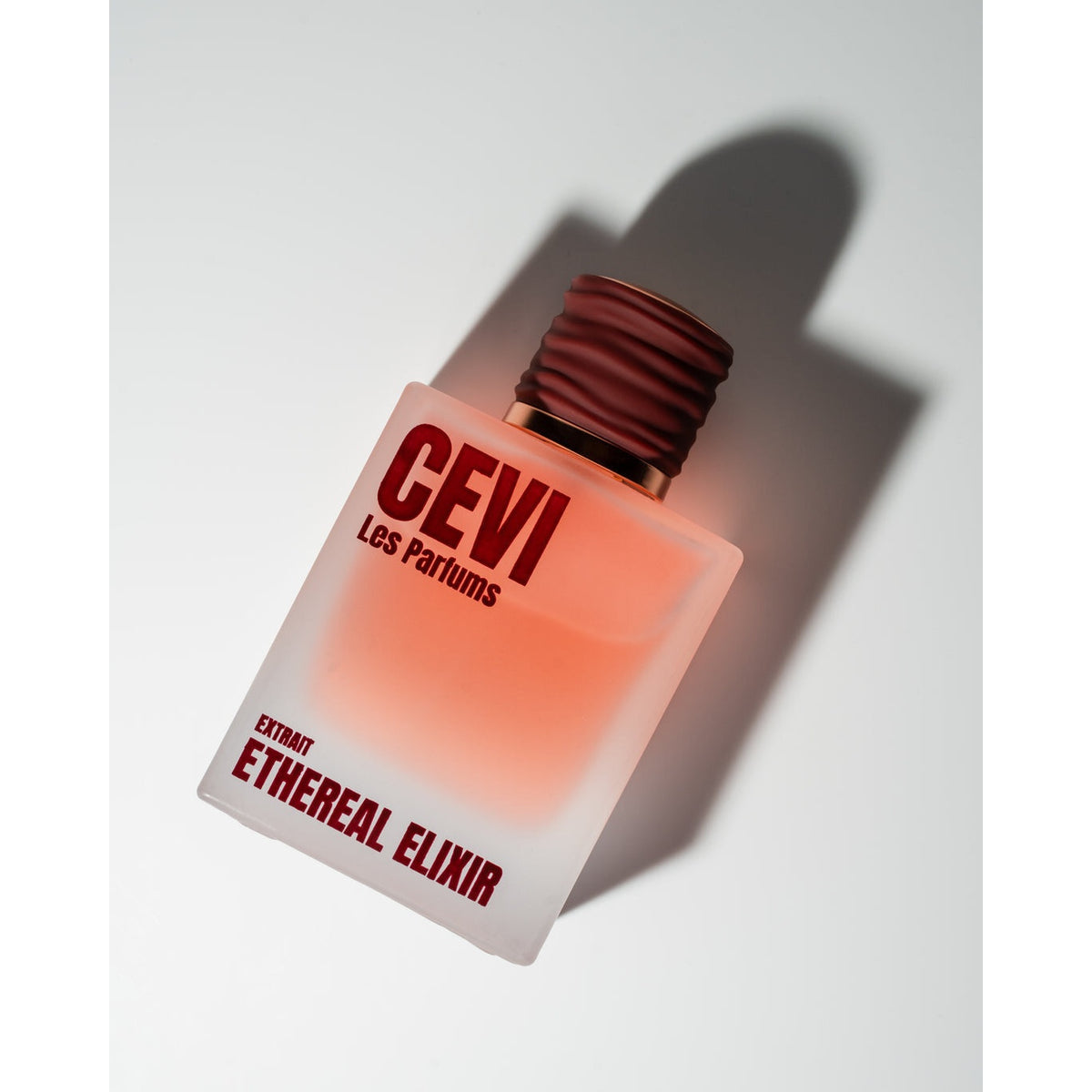 Ethereal Elixir by Cevi Les Parfums frosted glass bottle with dark red cap, angled with a long shadow