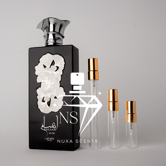 Black perfume bottle with floral design and gold caps on a gray background
