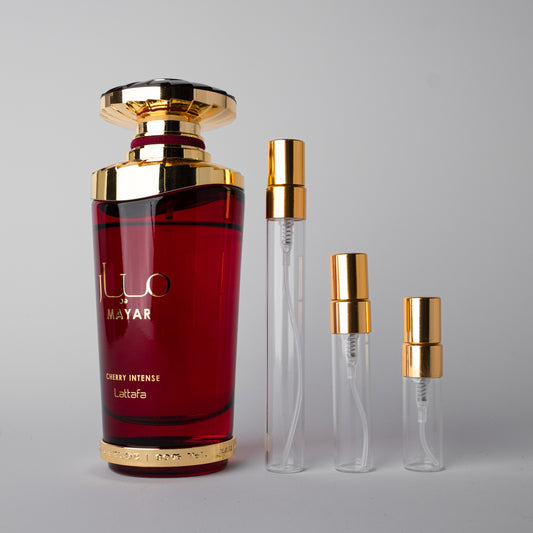 Red perfume bottle with gold cap and smaller clear bottles on a gray background