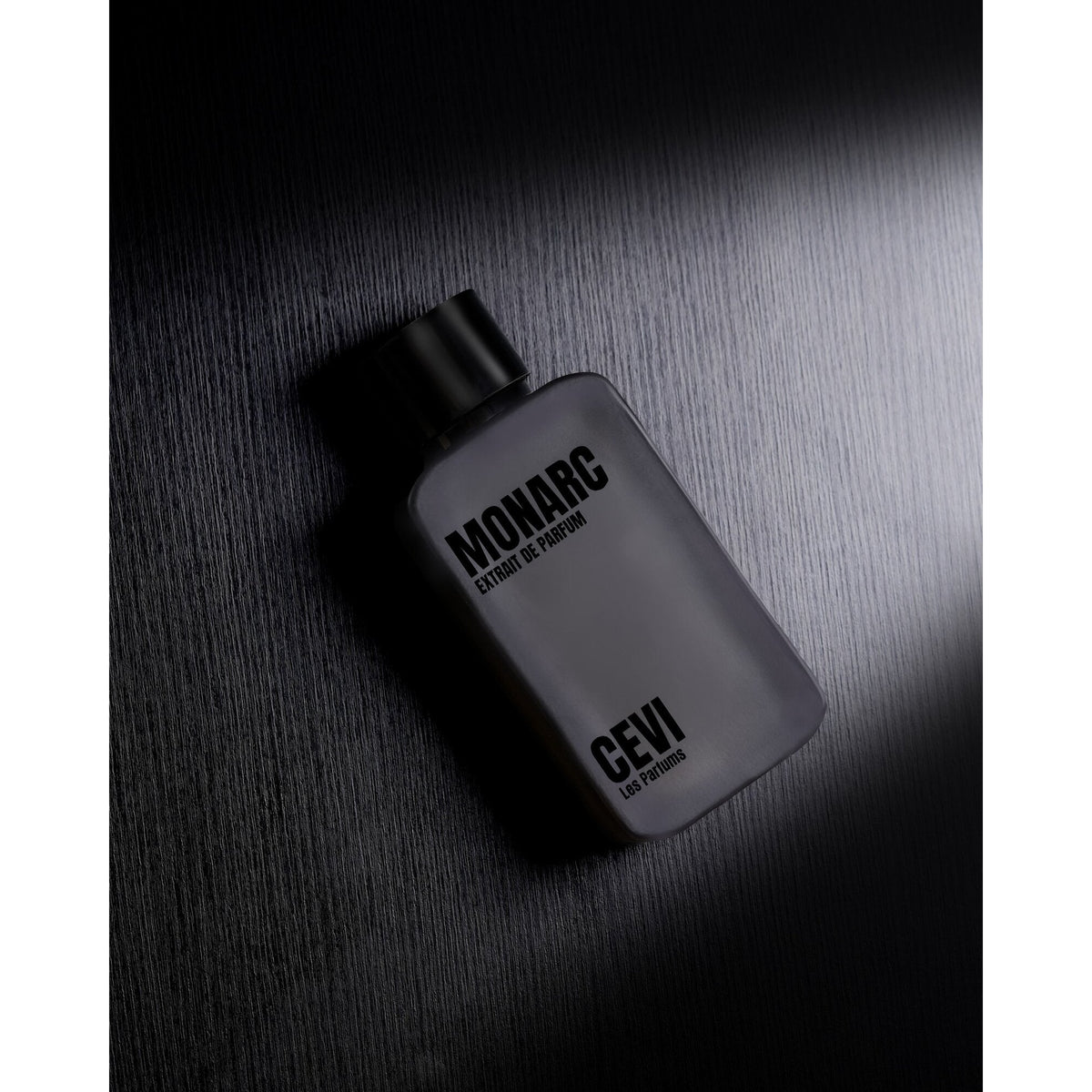 Monarc 100ml Extrait de Parfum bottle lying on a dark textured surface | Nuxa Scents