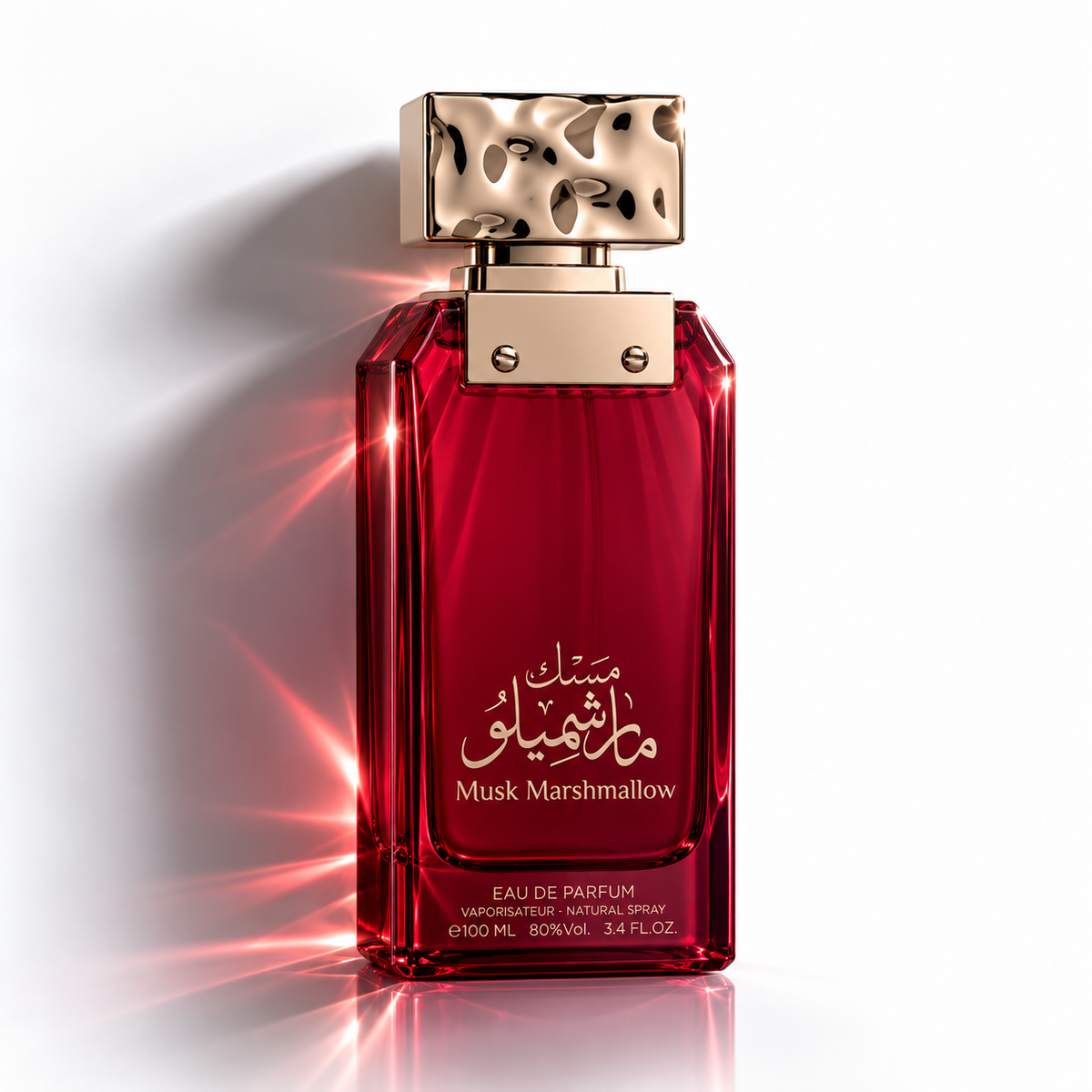 A bottle of Musk Marshmallow Eau de Parfum with a deep red glass body, a textured gold cap, and gold lettering on the front, set against a white background with a dramatic red light flare.