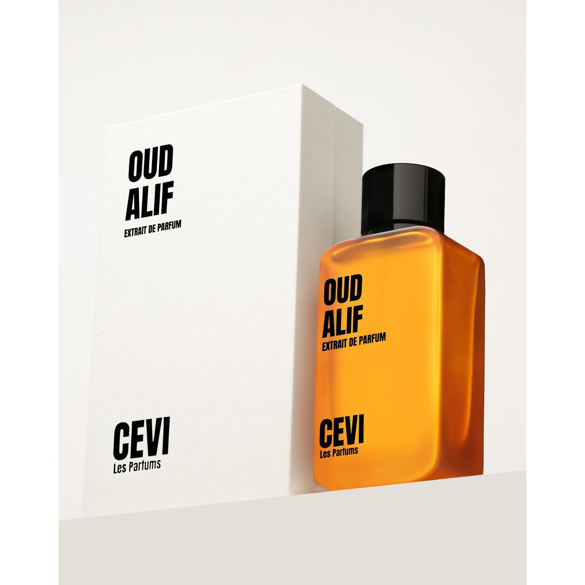 Cevi Oud Alif Extrait de Parfum amber-orange bottle with black cap in front of its white Oud Alif box