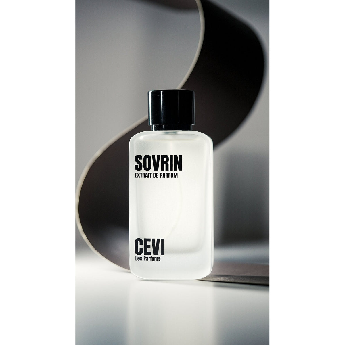 Sovrin by Cevi Les Parfums perfume bottle on a reflective surface with a curved silver-grey backdrop | Nuxa Scents