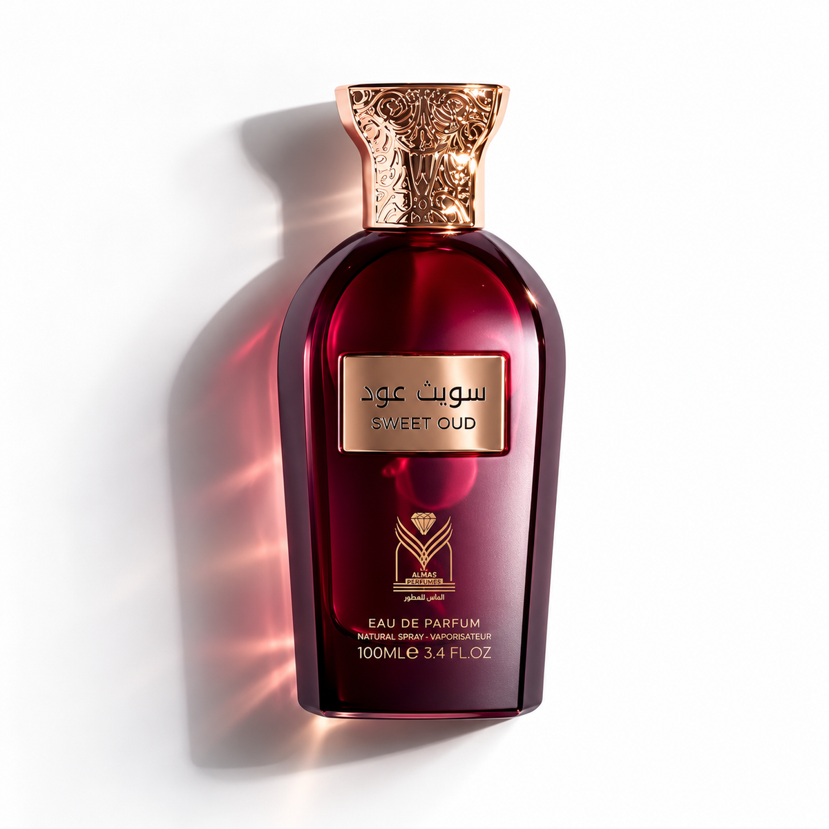 A bottle of Sweet Oud Eau de Parfum with a deep burgundy glass body, a metallic gold label, and an ornate gold cap, set against a clean white background with a soft shadow.