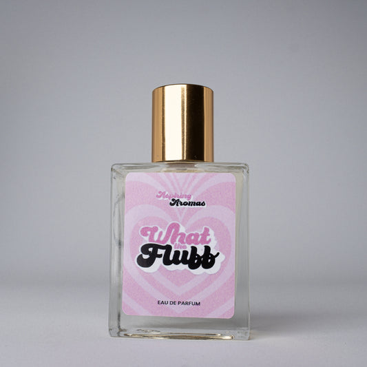 Perfume bottle with gold cap and pink label on a gray background with aspiring aromas what the fluff branding